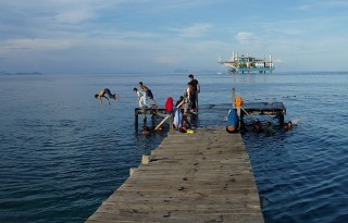 Local kids playing on the jetty at Borneo Divers - Seaventures Resort in the background